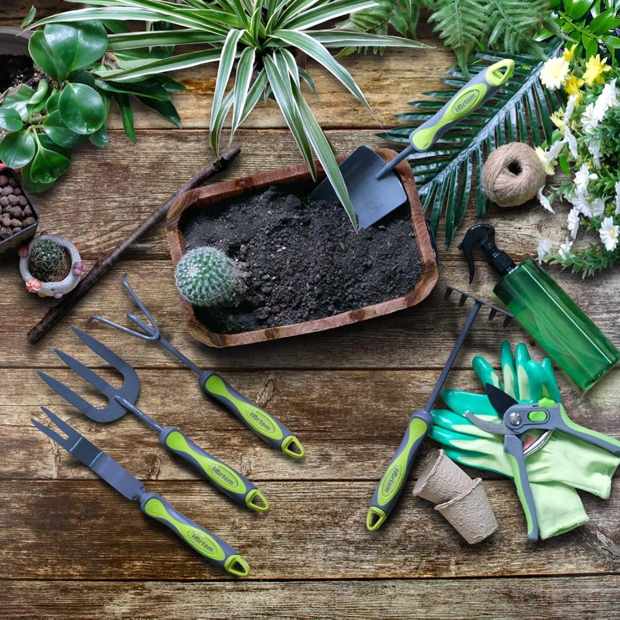 Ein Gartenwerkzeug-Set mit Blumenkelle, Kleinrechen, Doppelhacke, Blumengabel, Gartenschere und Sprühflasche auf einem Holztisch. Perfekt für die Pflege von Gemüsegärten und Bauerngärten.