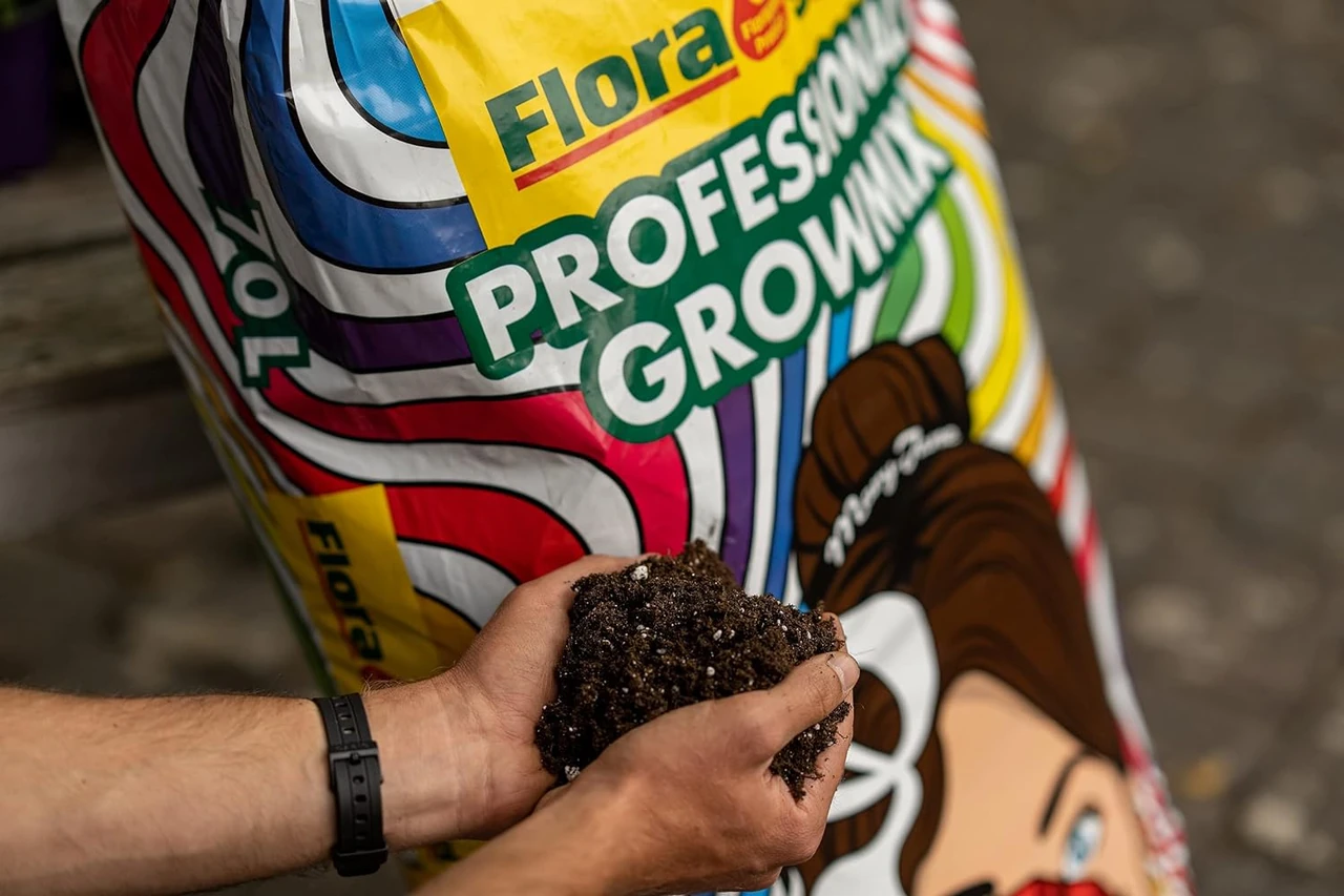 Hände halten hochwertige Pflanzenerde vor einem Sack mit professioneller Blumenerde, ideal für Blumentöpfe aus Ton, erhältlich bei OBI und Dehner.
